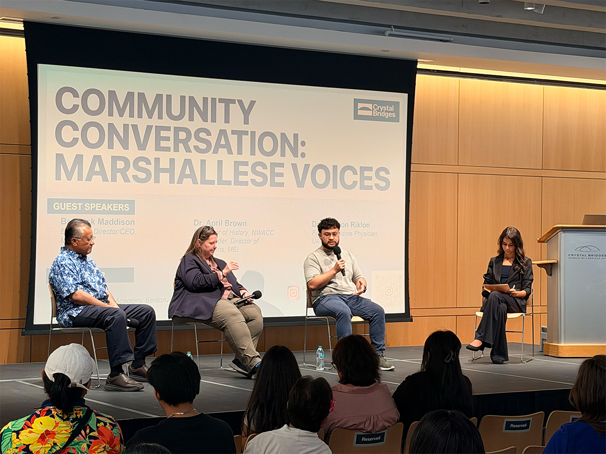 The conversation under way, seen from the back of a full room.